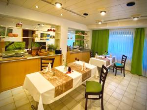 a restaurant with two tables and a kitchen with green curtains at Meister BÄR HOTEL Am Wald in Marktredwitz