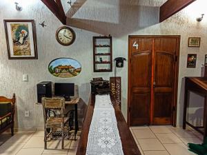 a room with a table and a desk and a clock at Hospedagem Braga - acomodação domiciliar in Cunha