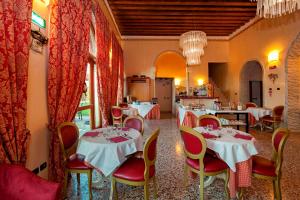 a restaurant with white tables and chairs and a kitchen at Albergo Antica Corte Marchesini in Campagna Lupia