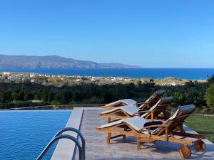 a row of lounge chairs sitting on the edge of a pool at ARIALKiS - ΑΡΙΑΛΚίΣ in Plataniás