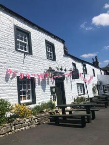 a white building with a picnic table in front of it at Queens Arms Litton in Litton