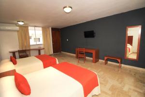 a hotel room with two beds and a table and a television at Hotel Central in Veracruz