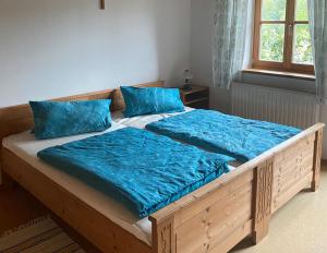 una gran cama de madera con almohadas azules. en Ferienwohnungen Wolfgang Geistanger, en Siegsdorf