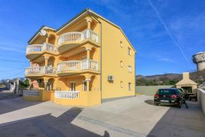 a yellow building with a car parked in front of it at Apartments KULAS in Novi Vinodolski