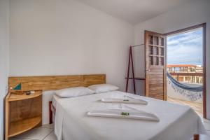 a bedroom with a bed and a view of the ocean at Convés Pousada in Barra de São Miguel