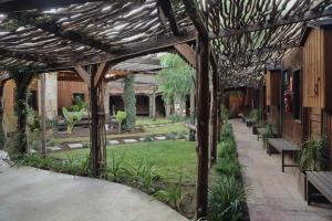 a wooden pergola with benches in a garden at Hotel Valle 13 Ruta del Vino in Valle de Guadalupe