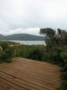 a wooden deck with a view of a body of water at Casa de praia na beira do mar in Florianópolis