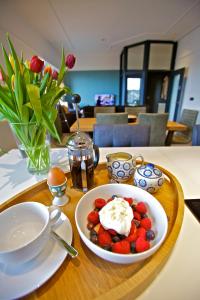 a table with a plate of strawberries and whipped cream at Northlight Apartments - The Lookout in Kirkwall
