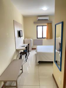 a bedroom with a bed and a desk and a mirror at Palácio Do Rio Hotel in Teresina
