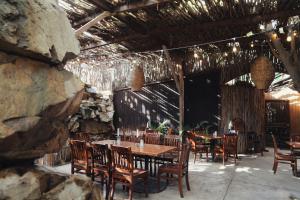 a restaurant with wooden tables and chairs and a stone wall at Hotel Valle 13 Ruta del Vino in Valle de Guadalupe