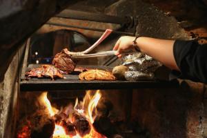 a woman is cooking meat on a grill at Hotel Valle 13 Ruta del Vino in Valle de Guadalupe