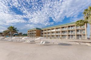 a hotel on the beach with chairs and palm trees at Ocean Breeze Inn Vero Beach in Vero Beach