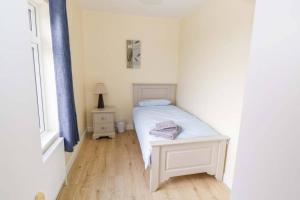 a small bedroom with a white bed and a window at John & Margarets Place in Ballinamore