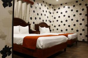 duas camas num quarto de hotel com papel de parede floral em El Regio em Monterrey