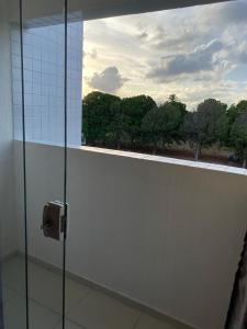 ein Bad mit einer Glasdusche und einem Fenster in der Unterkunft Residencial Havaí in João Pessoa
