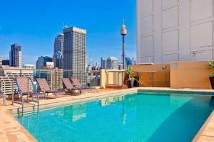 a swimming pool on top of a building with a city skyline at Accommodation Sydney: Hyde Park View 2 Bedroom 1 Bathroom Pet Friendly Apartment in Sydney