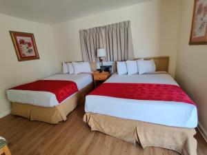 Cette chambre d'hôtel comprend 2 lits avec des draps rouges. dans l'établissement Crown Inn, à Fort Lauderdale