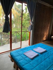 Cama azul en habitación con ventana en Nông Trại Thảnh Thơi en Ben Tre