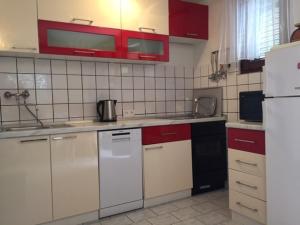 een keuken met witte apparaten en rode kasten bij Apartments and rooms Makaj - 80 m from the beach in Basina