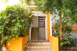 a yellow house with stairs leading to a white door at Secreto Hostel in Cartagena de Indias