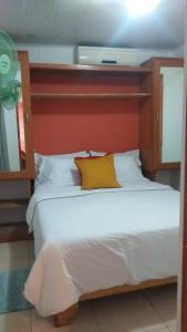 a bed with a yellow pillow on top of it at small apartment in Santo Domingo