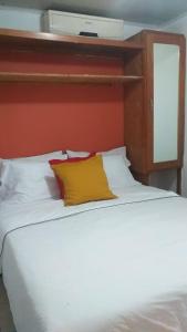 een groot wit bed met een geel kussen erop bij small apartment in Santo Domingo