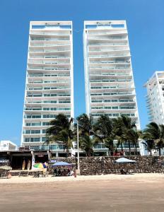 dois edifícios altos junto a uma praia com palmeiras em Resort Playa Azul 3 Dormitorios em Tonsupa