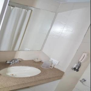 a white bathroom with a sink and a mirror at Regency Square Hotel in Gwalior