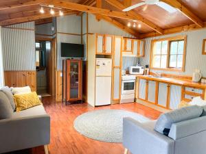 a living room with a white refrigerator and a kitchen at Port Bayou Cottage in Port Campbell