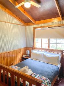 1 dormitorio con cama, techo de madera y ventana en Port Bayou Cottage, en Port Campbell