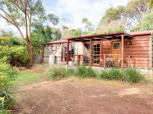 a wooden cabin with a table and chairs in it at Port Bayou Cottage in Port Campbell