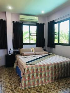 邦濤海灘的住宿－Tan ROCK RESORT，一间卧室设有一张大床和两个窗户。