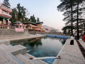a woman standing next to a pool of water at Yes Comfort Villa Guest House in Dharamshala