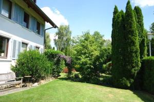 een tuin van een huis met een bank en bomen bij Romantische Ferienwohnung mit Nähe zum See in Oberteuringen