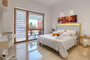 Dormitorio blanco con cama y ventana grande en Appartamenti LUNA e SOLE, en Roma