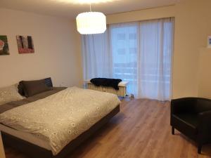 een slaapkamer met een bed en een stoel en een groot raam bij Dorfklatsch Ferienwohnung in Emmetten