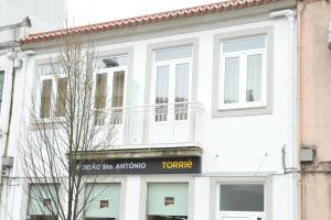 a white building with a sign on the front of it at Pensão Santo António in Vila Nova de Famalicão