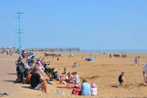 a crowd of people on a beach with a pier at Great Deals at The Grange, Ingoldmells in Skegness