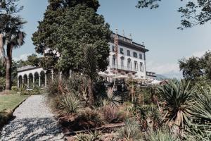 una grande casa bianca con palme e piante di Hotel Villa Emden a Brissago