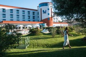Una donna che cammina sull'erba di fronte a un edificio di Lu' Hotel Carbonia a Carbonia