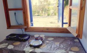 a table with a plate and two cups and a window at Isavella's Apartment in Schinoussa