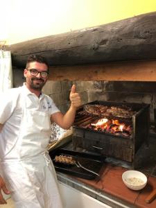 Un homme donnant un pouce devant un grill dans l'établissement Agriturismo Bellosguardo, à Reggello