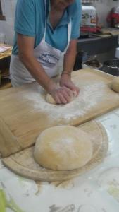 a woman kneading dough on a wooden cutting board at Agriturismo Bellosguardo in Reggello