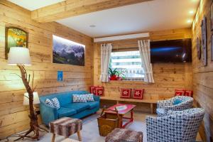 uma sala de estar com um sofá azul e cadeiras em Alpen Chalet em Schilpario