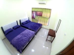 sypialnia z fioletowym łóżkiem i krzesłem w obiekcie South City Homestay in Wirokerten w mieście Bantul