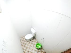uma casa de banho com um WC branco e uma tigela verde em South City Homestay in Wirokerten em Bantul