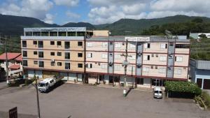 a large pink building with cars parked in a parking lot at Hengu Hotel in Encantado