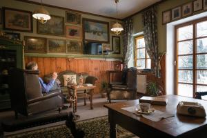 a man sitting in a chair in a living room at Dworek pod Herbem in Gądkowice