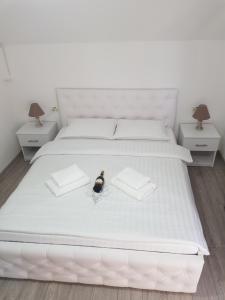 a white bed with a bottle of wine sitting on it at Casa Sima in Curtea de Argeş