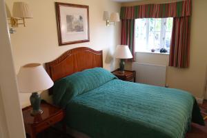 a bedroom with a bed with a green comforter and two lamps at Red Lion Dunston in Branston